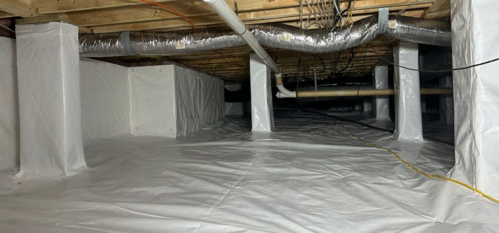 Encapsulated crawl space with a sealed vapor barrier covering the floor and support piers, along with insulated ductwork and framing above.